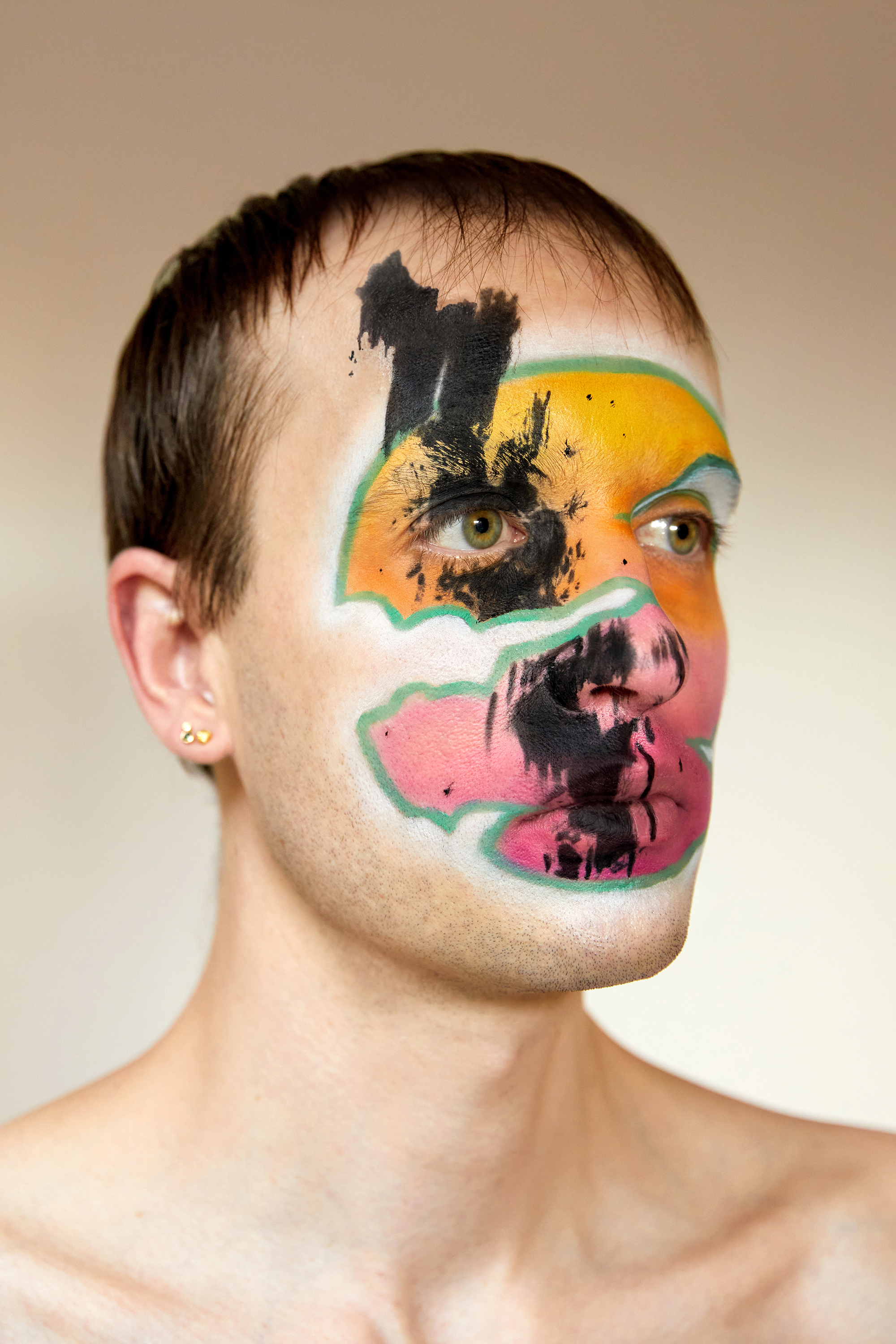Jesse Clark posing his hand on one side of his head with black and white facepaint that resembles a mountain range against a white background